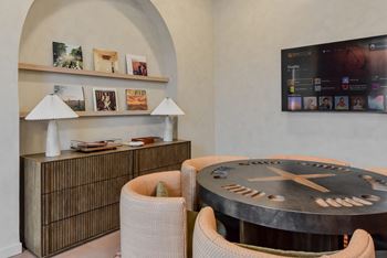 A modern living room with a round table and a flat screen TV mounted on the wall.